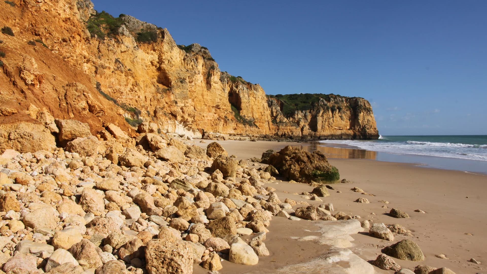 Golden sandstone cliffs above a sandy beach on the Algarve coast, Portugal