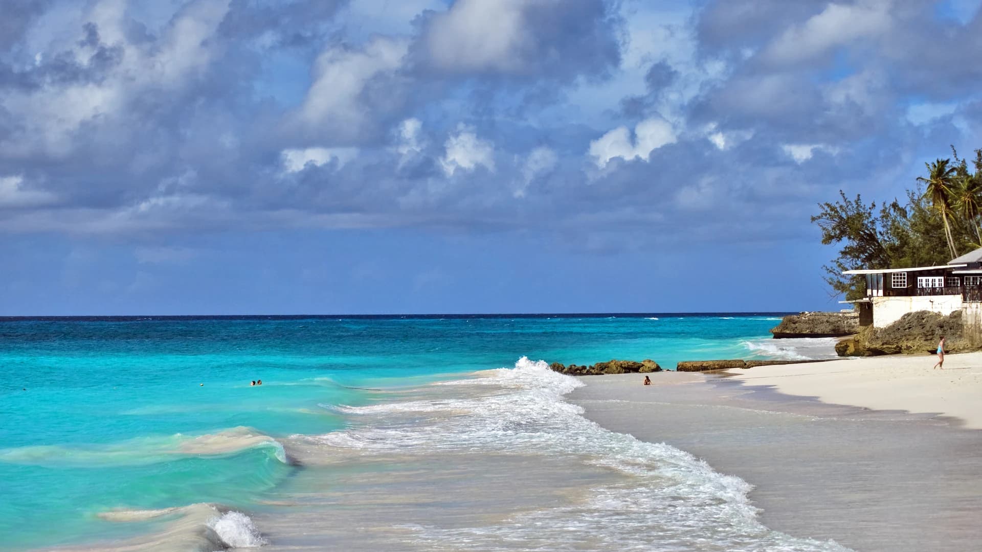 Waves rolling onto a white sand beach with turquoise water in Barbados