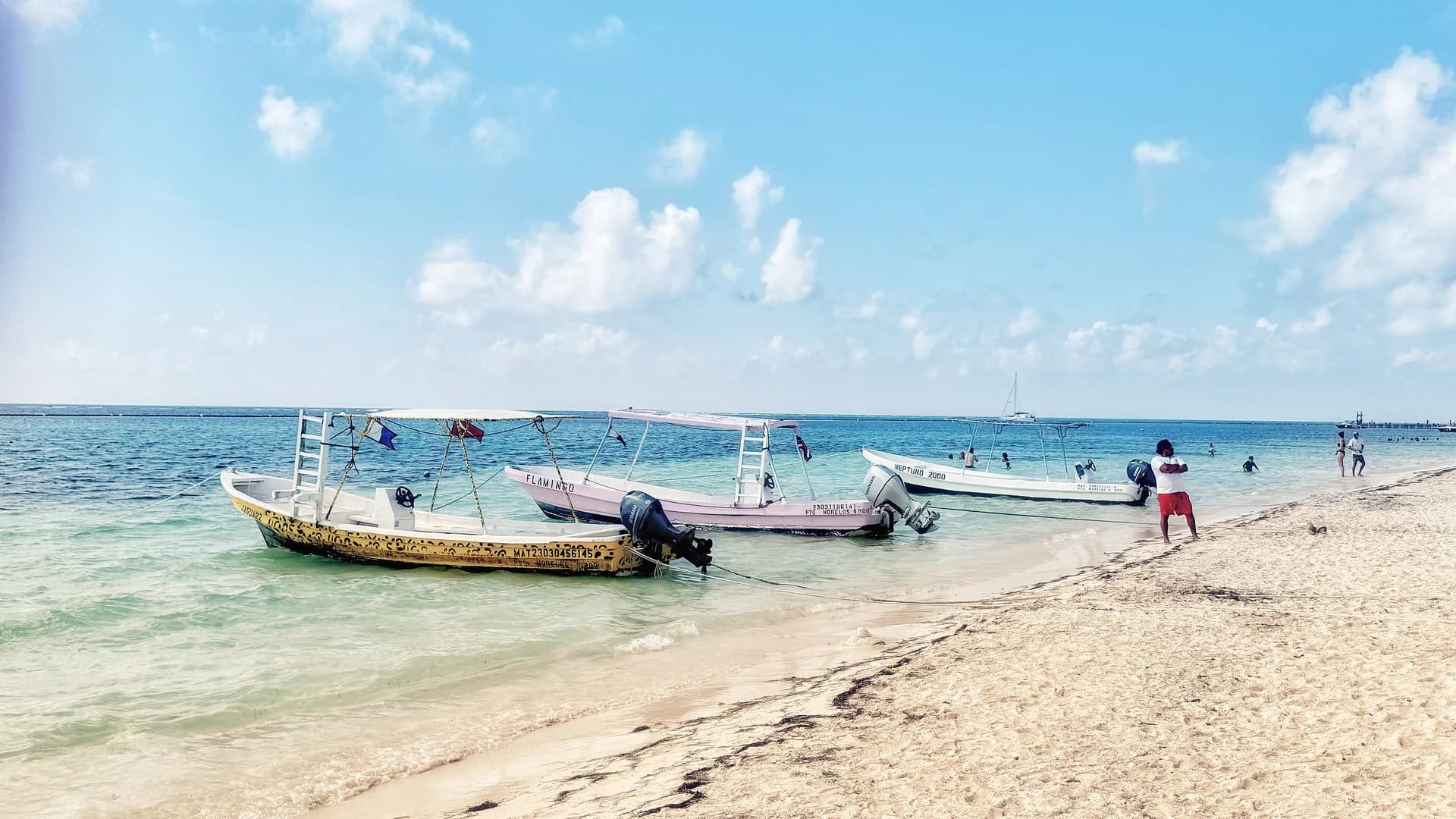 Snorkeling boats pulled up on the beach at Puerto Morelos, Quintana Roo, with the reef break visible offshore
