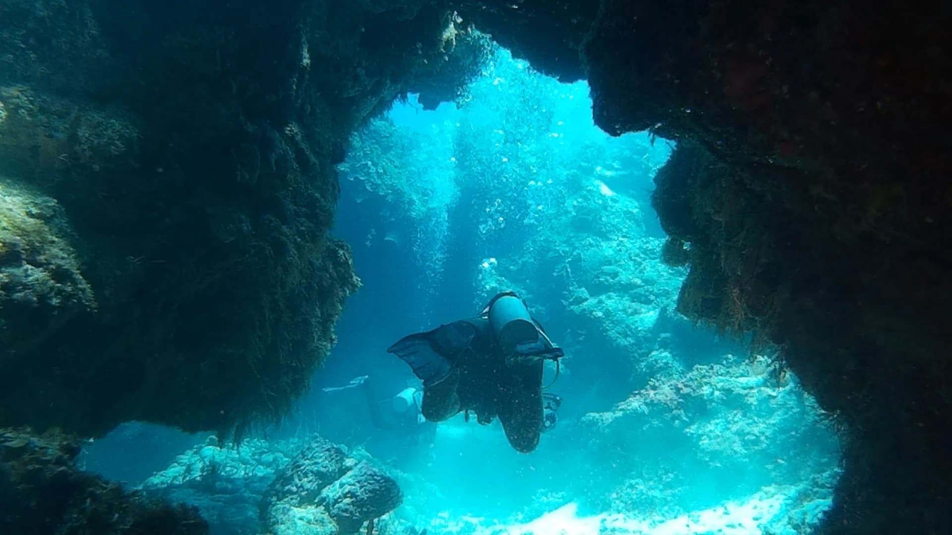 Scuba diver passing through a coral swim-through on Palancar reef, Cozumel, Mexico