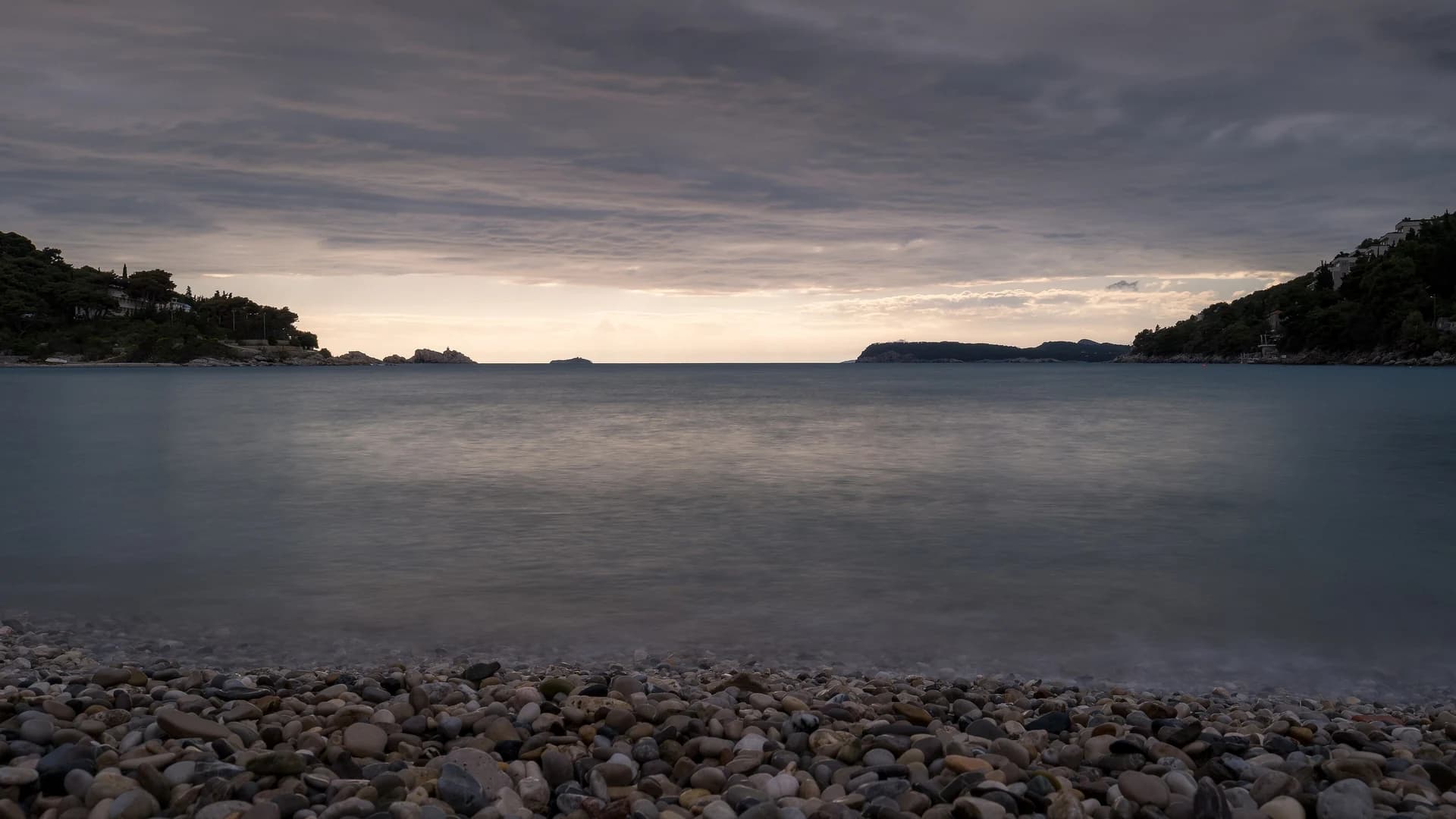 Pebble beach at dusk near Dubrovnik, Croatia, with the Adriatic coastline and offshore islands