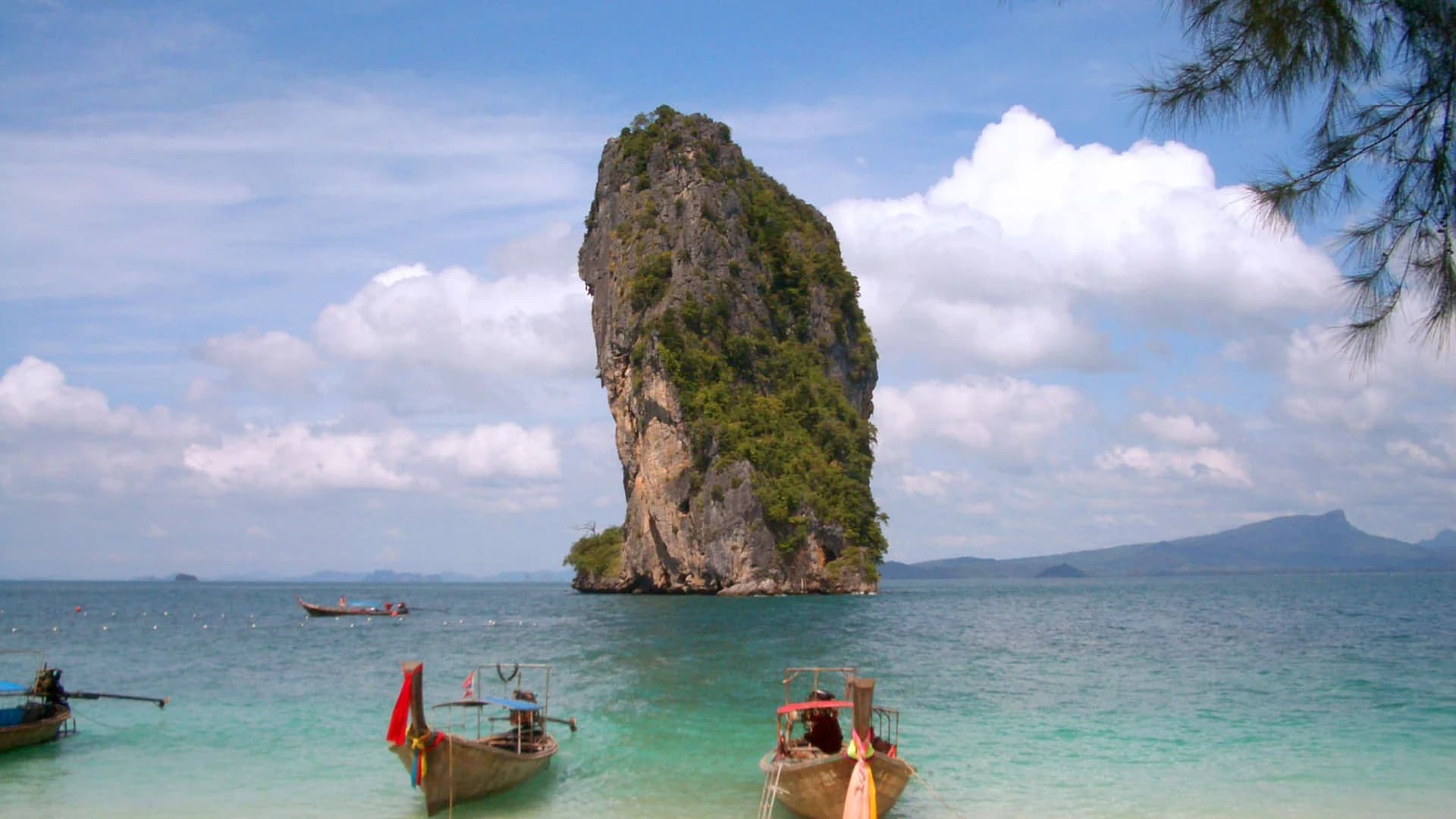 Longtail boats moored off Poda Island below limestone karsts, Krabi, Thailand