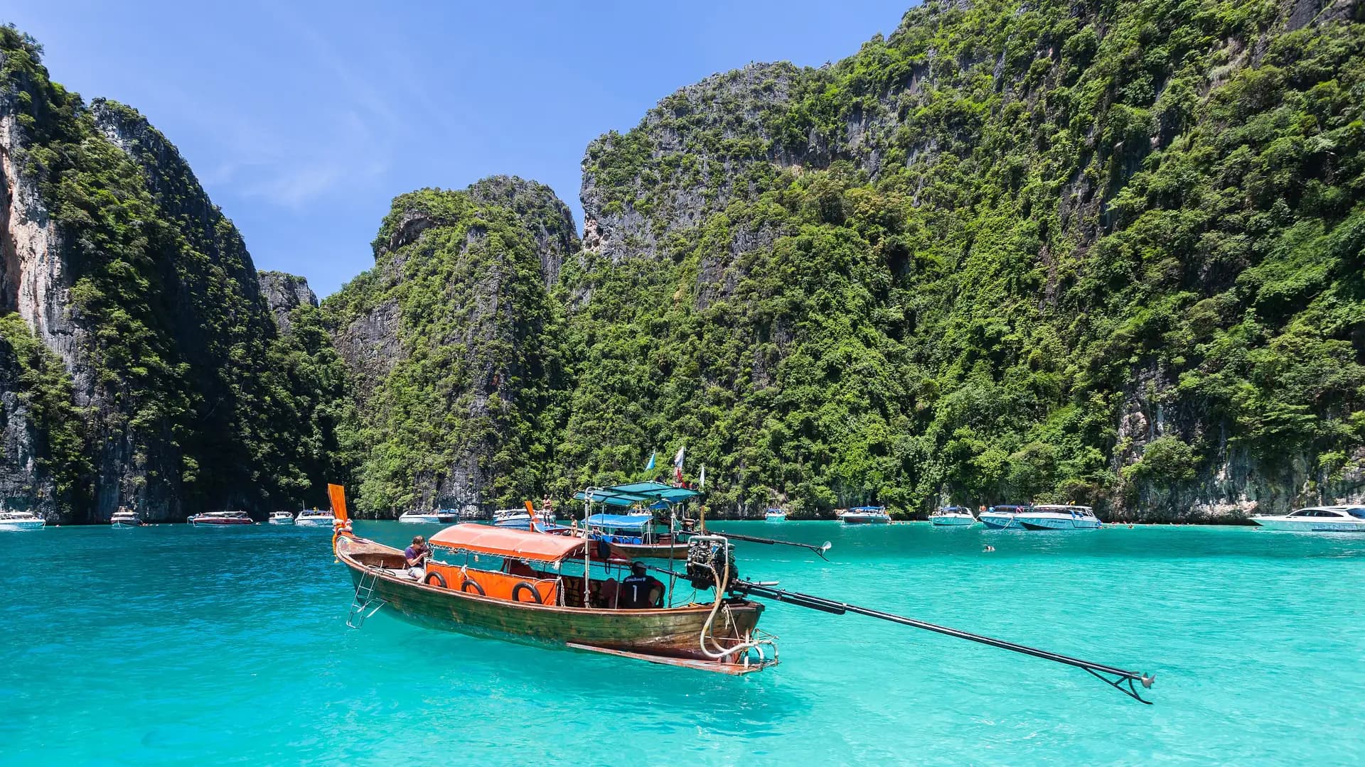 Longtail boat on turquoise water below the limestone cliffs of Phi Phi Leh, Thailand