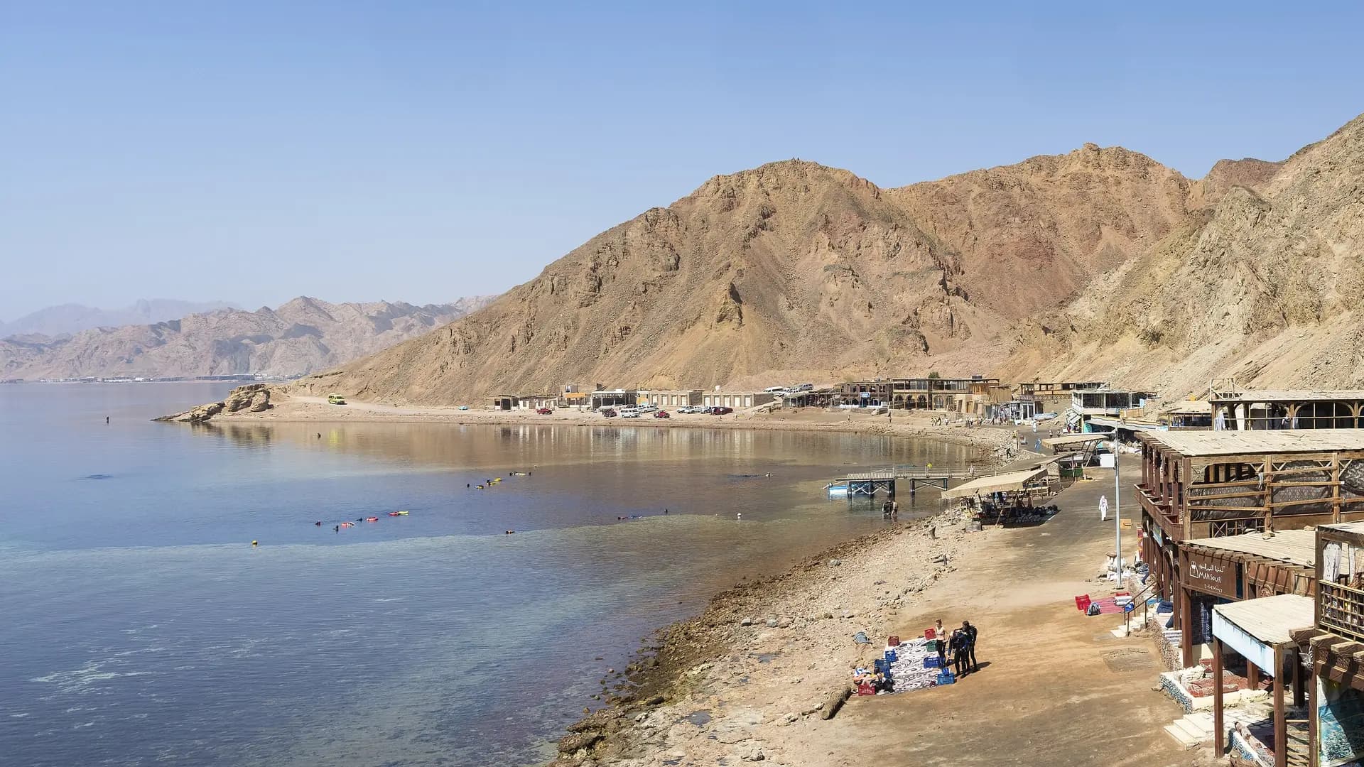 The coast at Dahab with Sinai mountains behind and snorkelers in the shallows, Egypt