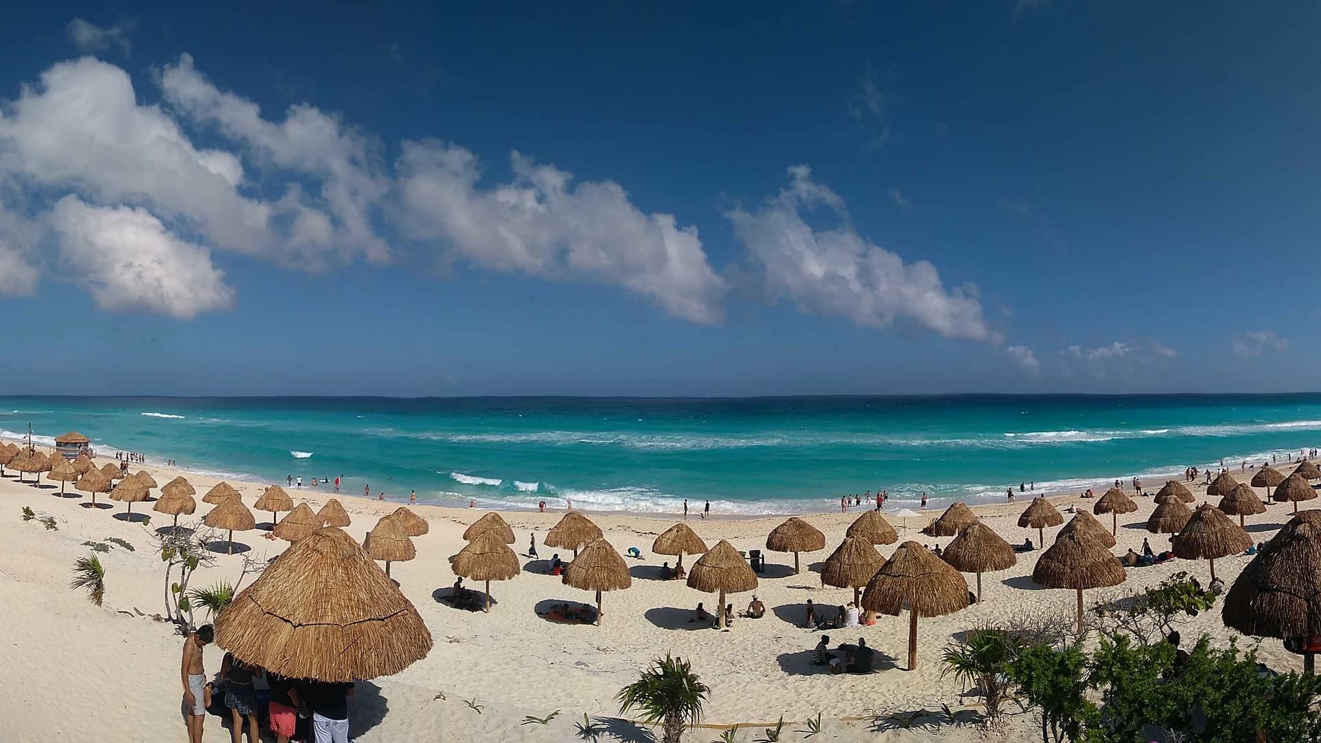 Playa Delfines in Cancún, Mexico, with palapas and turquoise Caribbean water along the hotel zone