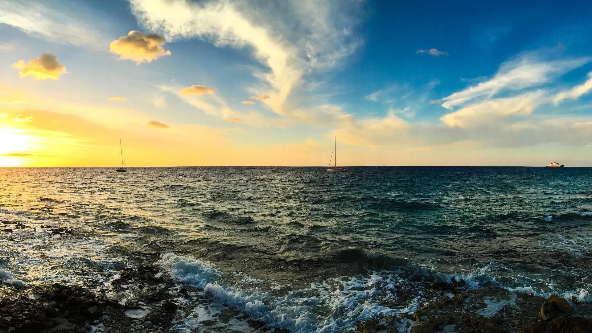 Sunset over the water at Cancún, Mexico, with sailboats anchored offshore