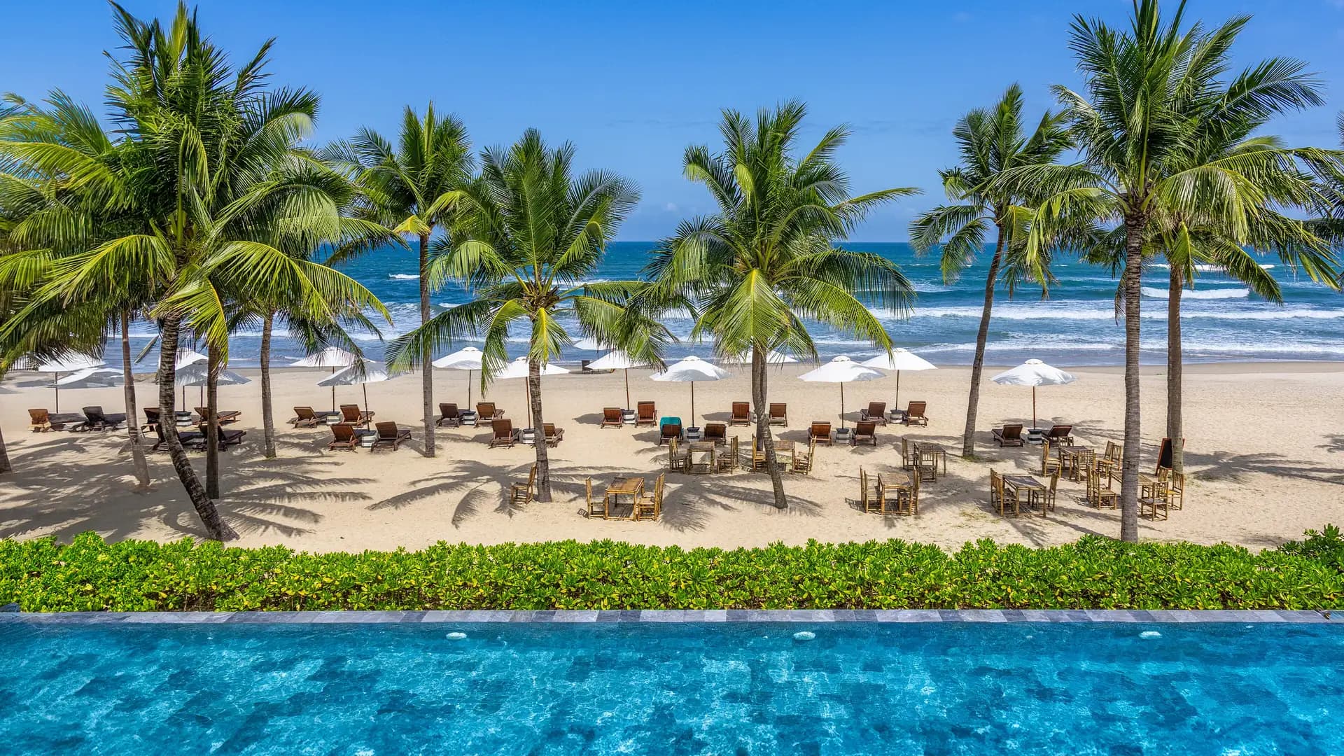 Palm trees, loungers, and turquoise water along My Khe Beach, Da Nang, Vietnam