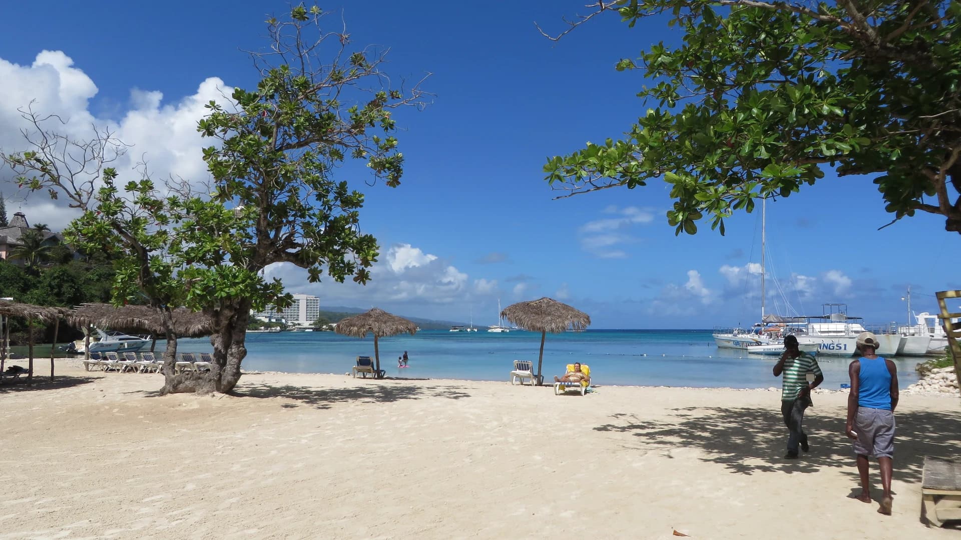 Mahogany Beach in Ocho Rios, Jamaica, with palm trees and boats in the bay